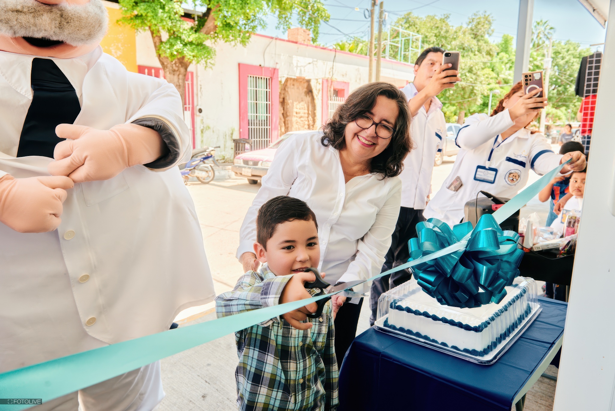 Niño cortando listón de inauguración de Farmacias Similares del Dr. Simi en Badiraguato